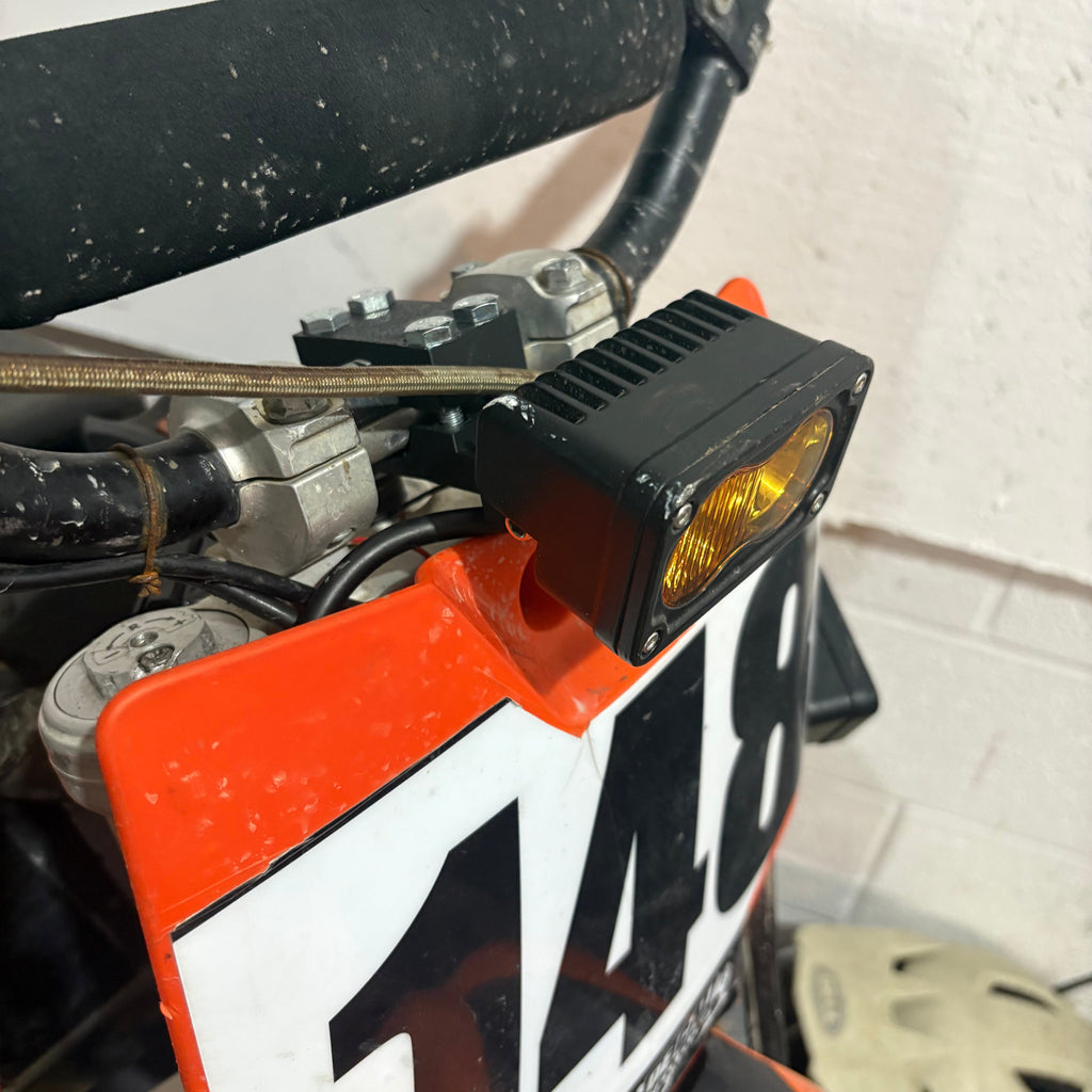 Close-up of a dirt bike with a visible brand logo on a white background