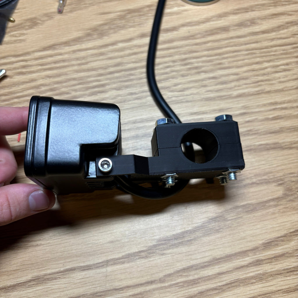 Black metal bracket with wiring on a wooden surface