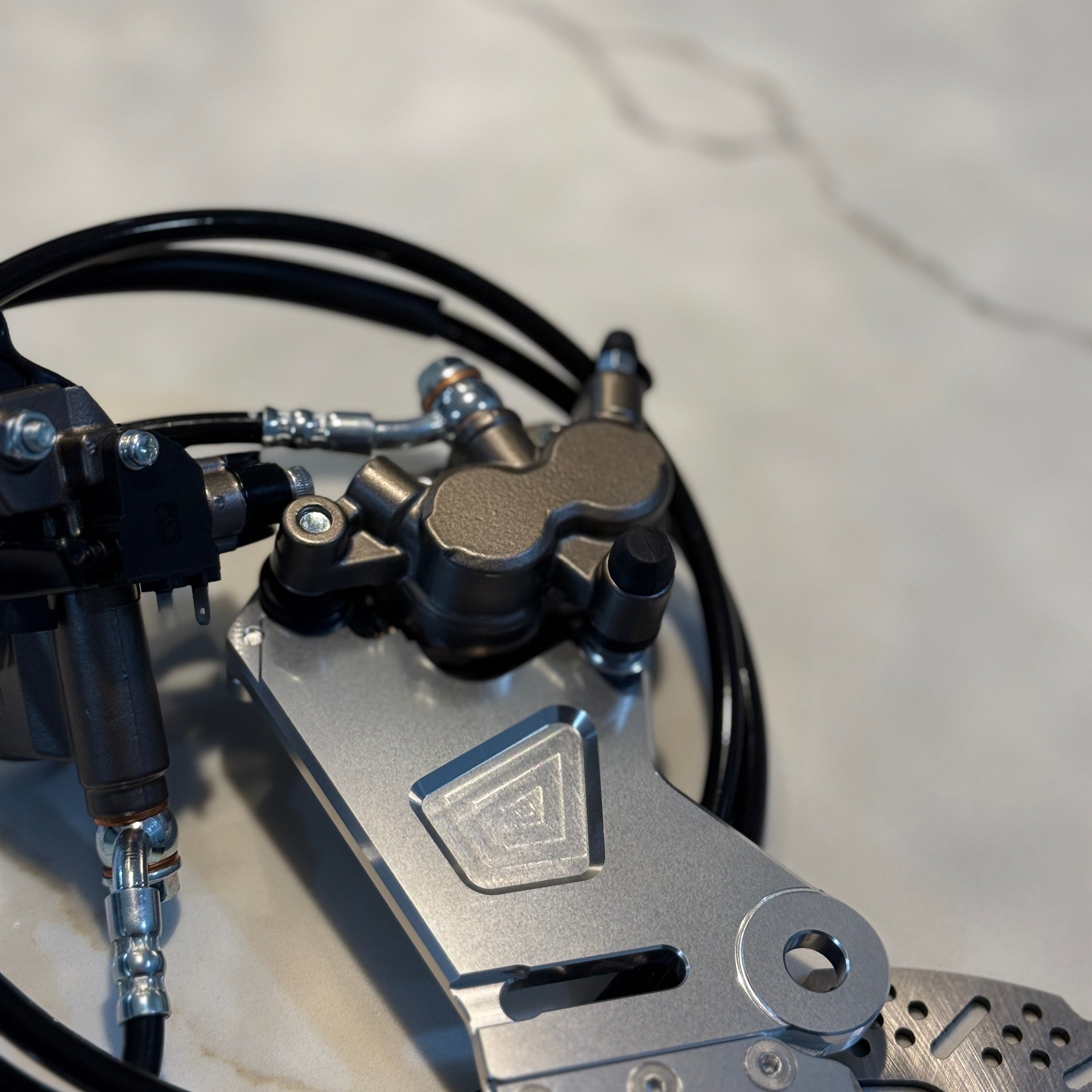 Close-up of a motorcycle brake lever and caliper on a light gray background