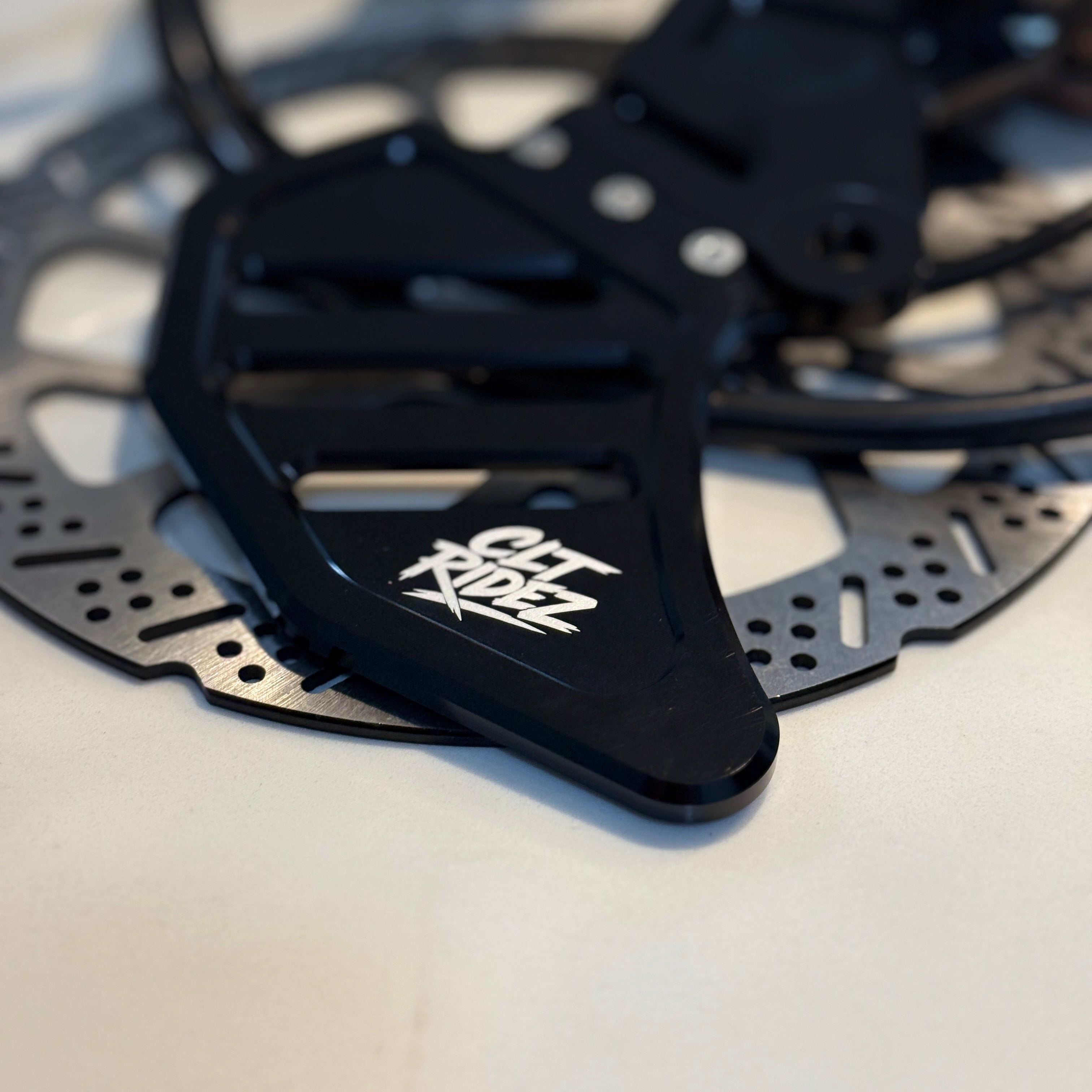 Close-up of a black bicycle disc brake rotor with a brand logo on a white background