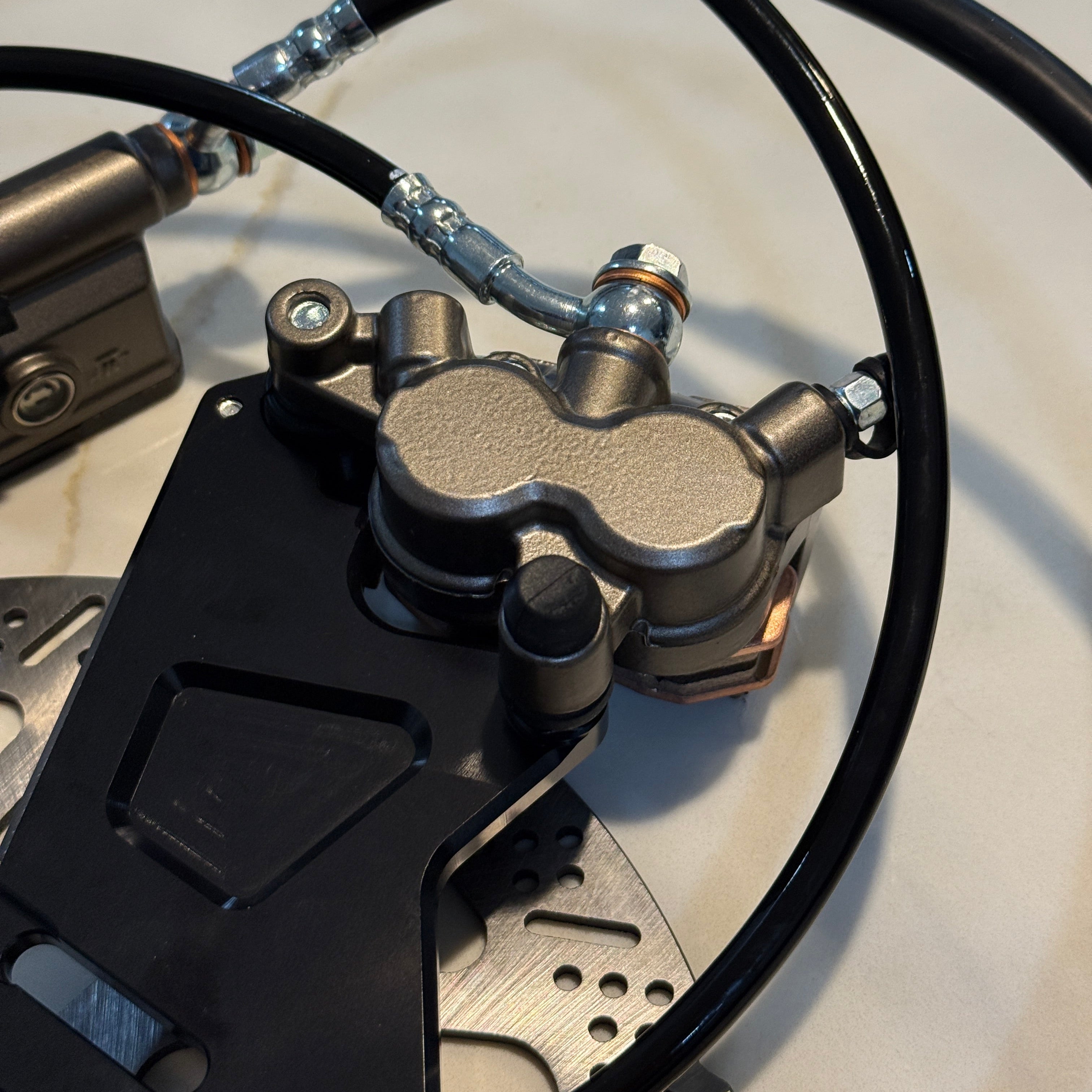 Close-up of a motorcycle brake system with caliper, rotor, and cables.