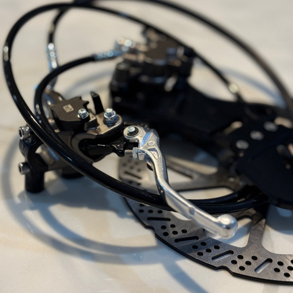 Close-up of a bicycle brake mechanism with cables and a disc rotor.