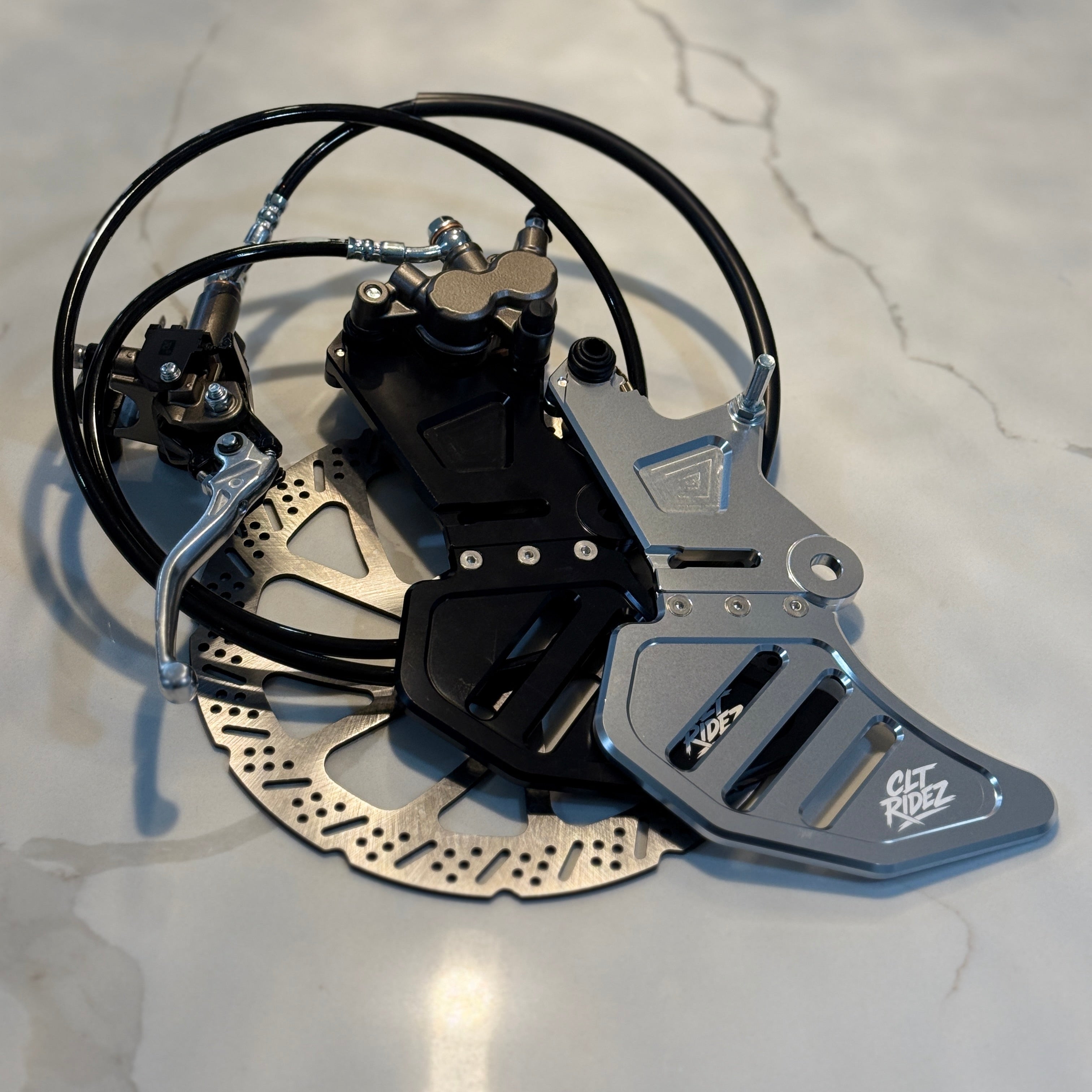 Metallic brake rotor with caliper on a light-colored surface