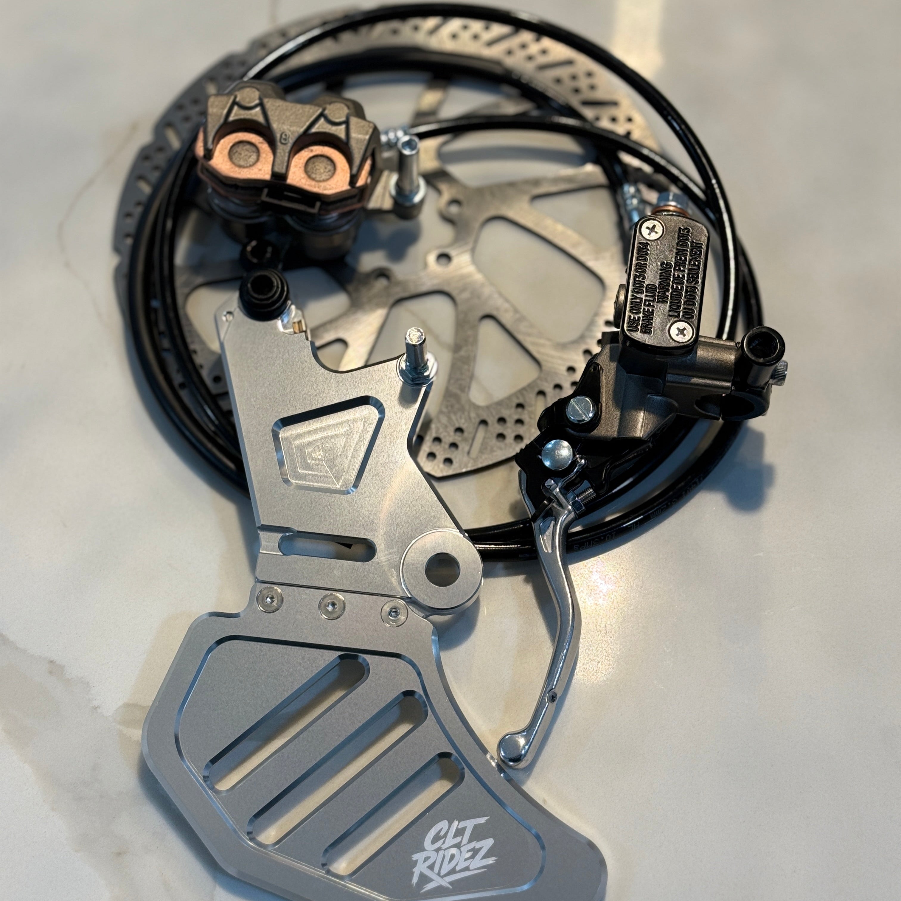 Close-up of a motorcycle foot peg and brake lever on a light background