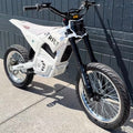 White electric bike with black accents parked against a gray wall.
