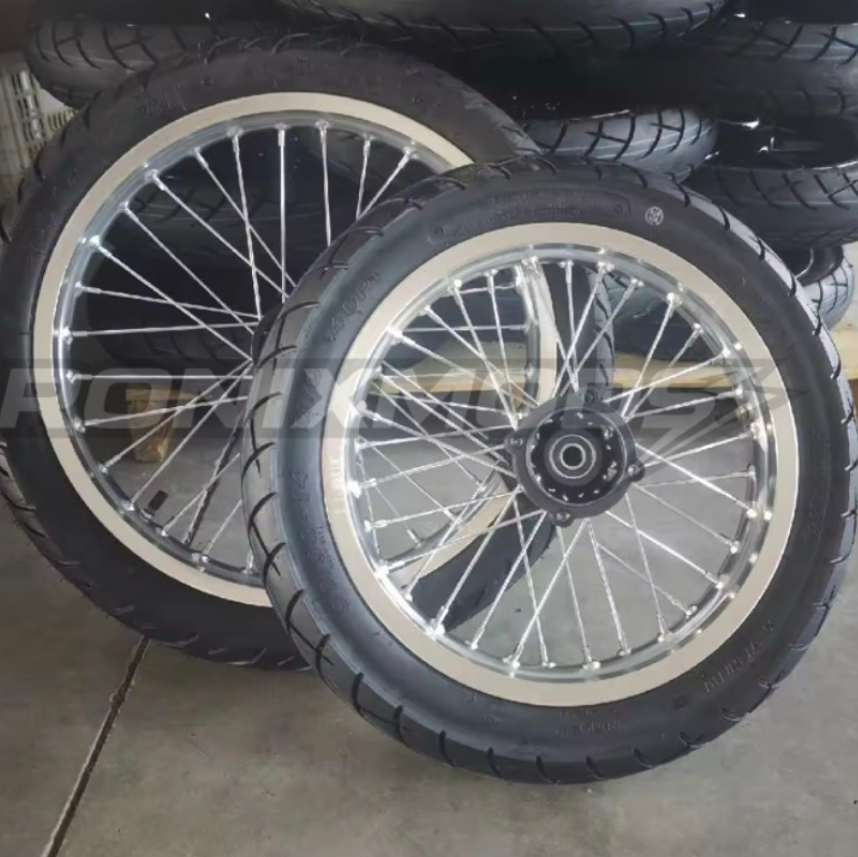 Motorcycle wheels with black tires and silver spokes on a concrete floor.
