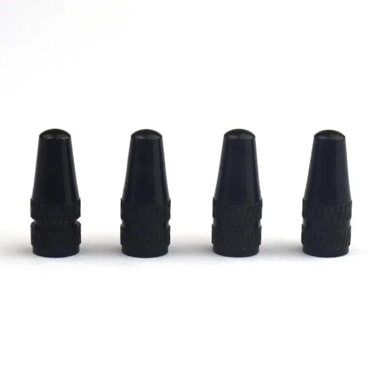 Four black tire valve stems on a white background