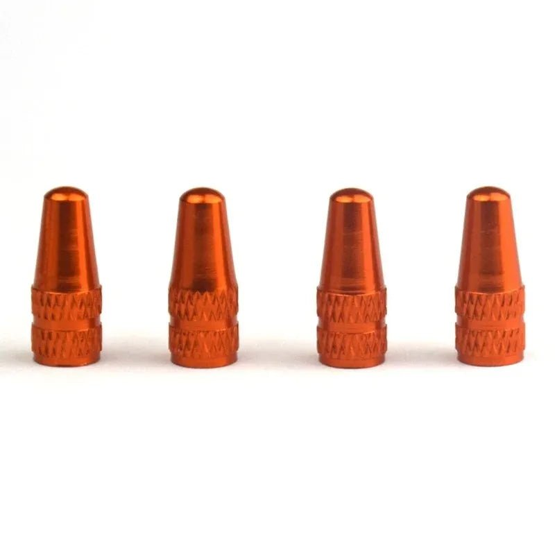 Four orange metal valve stem caps on a white background